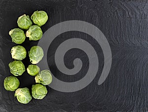 Fresh raw organic brussel sprouts on black stone setting
