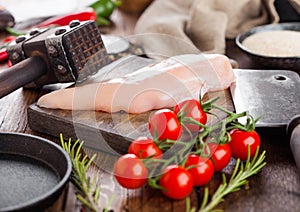 Fresh Raw Organic Chicken Fillet Breast on vintage board with meat hatchets and spices with herbs on wooden background. Tomatoes