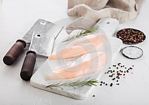 Fresh Raw Organic Chicken Fillet Breast on white marble board with meat hatchets and spices with herbs on white background