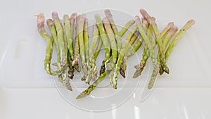 Fresh raw organic green asparagus close up on white cutting board