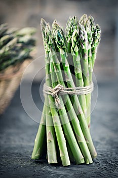 Fresh raw organic green Asparagus sprouts closeup. Over wooden table. Healthy vegetarian food. Raw vegetables, market