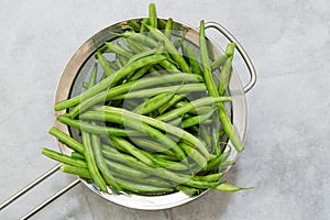 Fresh raw organic green beans, haricots verts, close-up in colander, flat lay photo