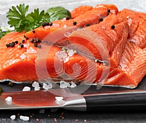 Fresh raw pacific wild king salmon fillets on natural stone with spices and basil leaves