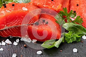 Fresh raw pacific wild sockeye salmon fillets on natural stone with spices and basil leaves