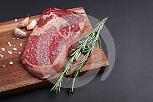 A fresh raw piece of black angus marbled meat with spices close-up on a stone dark background. Ribeye steak