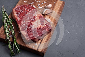 A fresh raw piece of black angus marbled meat with spices close-up on a stone dark background. Ribeye steak