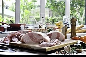 Fresh raw pieces of pork meat with ingredients for cooking on a cutting board in the kitchen