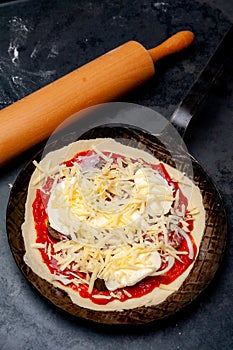 Fresh raw Pizza in an rustic iron Pan
