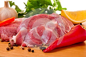 Fresh raw pork on board with fresh vegetables