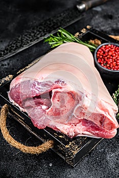 Fresh Raw pork Eisbein knuckle ham in a wooden tray with meat knife. Black Wooden background. Top view