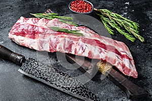 Fresh Raw pork rack spare ribs with spices on a cutting board with knife. Black background. Top view