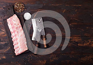 Fresh raw pork ribs on chopping board and vintage hatchets on wooden background. Pepper and salt. Space for text