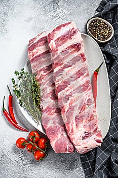 Fresh raw pork ribs with spices and herbs. Gray background. Top view