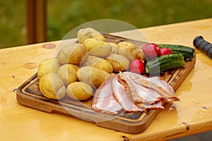 Fresh raw potatoes with meat and knife on wooden table