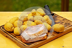 Fresh raw potatoes with meat and knife on wooden table