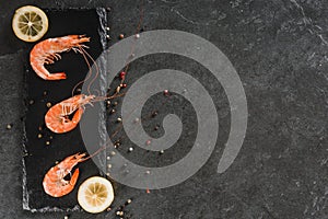 Fresh raw prawns or boiled red shrimps with spices on slate stone on dark stone background. Seafood, top view, flat lay