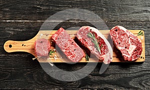 Fresh raw Prime Black Angus beef steaks on wooden board