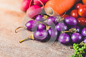 Fresh raw Purple Eggplant and various kinds of vegetables as background on wooden table