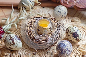 Fresh raw quail eggs in the nest on rustic straw and wooden vintage background