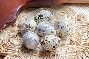 Fresh raw quail eggs on rustic straw and wooden vintage background