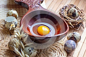 Fresh raw quail eggs in wooden spoon on rustic straw and wooden vintage background