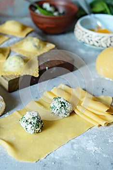 Fresh Raw Ravioli with Ricotta and Spinach on a blue background. Homemade raw uncooked italian pasta ravioli.