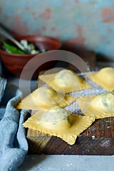 Fresh Raw Ravioli with Ricotta and Spinach on a blue background. Homemade raw uncooked italian pasta ravioli.