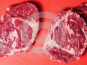 Fresh raw rib eye steak on a red cutting board. Premium cut of beef. Meat industry product