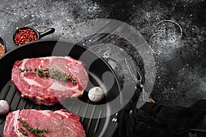 Fresh raw Rib eye Steak with seasonings, on black dark stone table background, with copy space for text