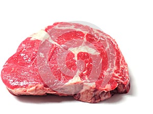 Fresh raw rib eye steak on a white surface.