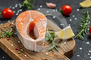 Fresh raw salmon fish steak with spices on dark wooden background