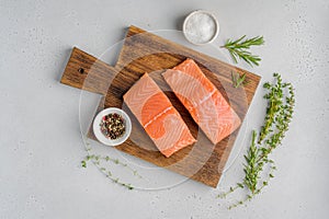 Fresh raw salmon humpback fillet on old wooden board. Rosemary, thyme, salt, pepper