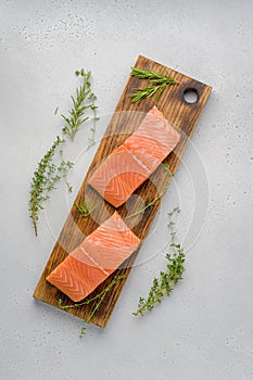 Fresh raw salmon humpback fillet on wood board. Rosemary, thyme, salt, pepper. Above