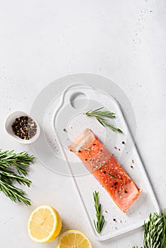 Fresh raw salmon red fish fillet with spieces, herbs and lemon on white background, side view. Restaurant menu, recipe. Copy space