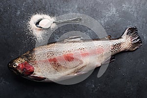 Fresh raw salmon red fish with with a spoon of organic pink salt on dark stone background. Creative layout made of fish
