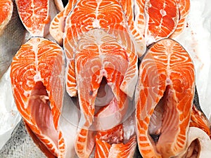 Fresh raw salmon steak slices for sale in the ice in market fridge. Red fish, showcase of fish store