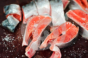 Fresh raw salmon steaks with salt on the rustic table