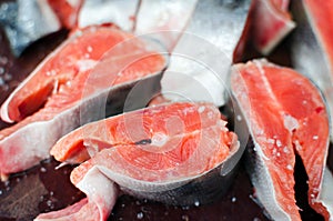 Fresh raw salmon steaks with salt on the rustic table