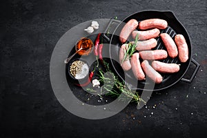 Fresh raw sausages on a cast-iron grill pan on a black background