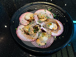 Fresh raw scallops in shell on a black dish