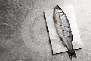 Fresh raw sea bass fish on light gray table, top view. Space for text