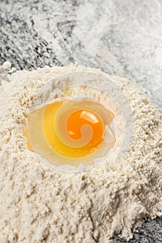 Fresh raw smashed egg in the white flour pile
