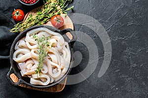 Fresh raw squid rings in a steel bowl. Black background. Top view. Copy space