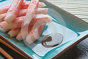 Fresh raw sushi crabsticks on plate with chopsticks