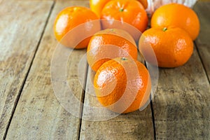 Fresh raw tangerines spilled from wicker basket on plank wood rustic table. Healthy food plant based diet citrus fruits vitamins