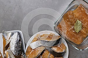 Fresh raw trout or salmon fish slices steak in white plate, head, fillet in glass bowl, with spices on stone background. Creative