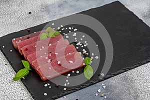 Fresh raw tuna steak with basil. On black rustic background