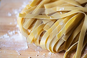 Fresh raw uncooked pasta - tagliatelle on a wooden board