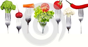 Fresh raw vegetables on forks on white background