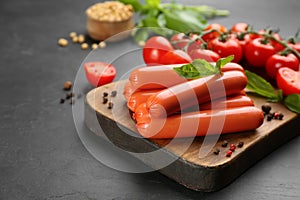 Fresh raw vegetarian sausages and vegetables on black table, closeup